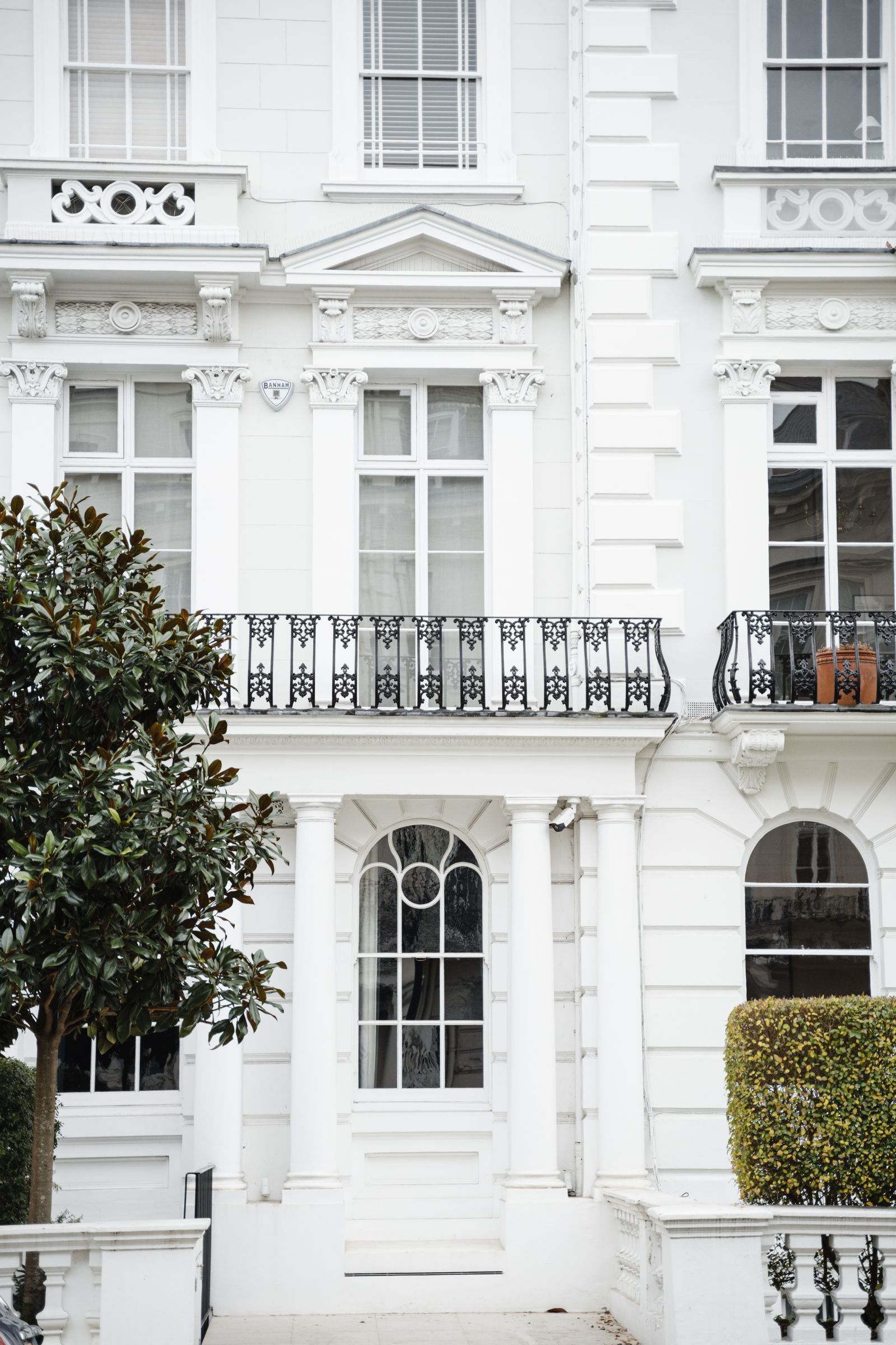 White London townhouses, framed by leafy trees and decorative iron balconies